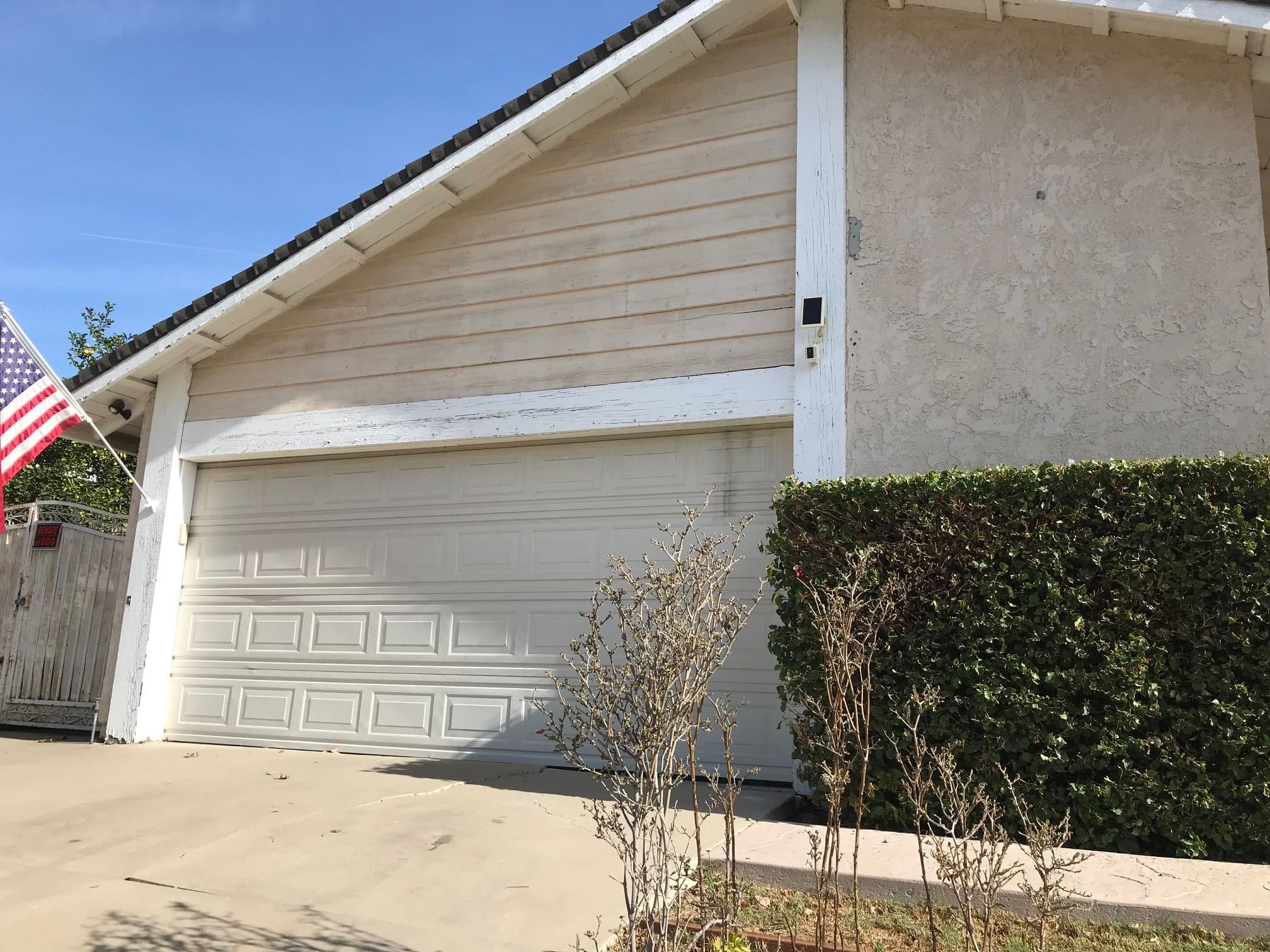 Residential garage with an American flag and landscaped front yard on a sunny day.