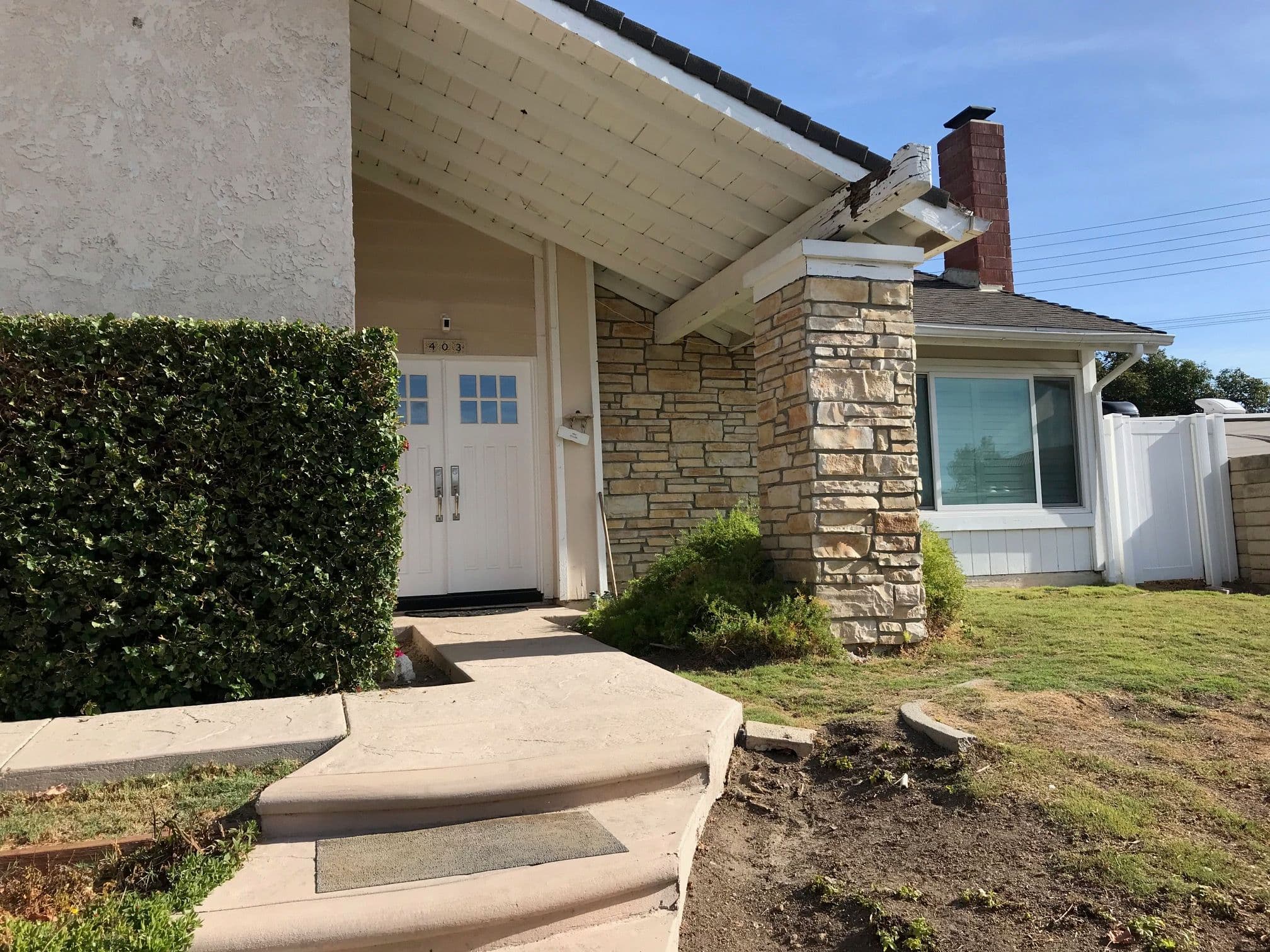 Modern single-family home entrance with stone accents and a well-maintained lawn.