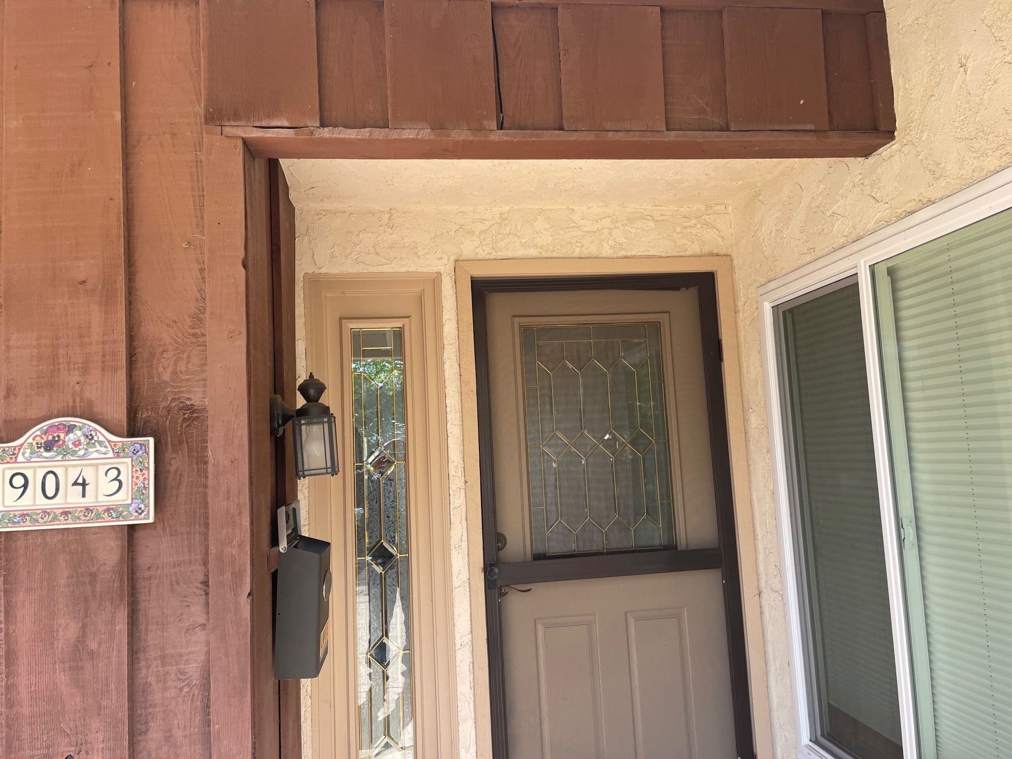Front entryway of a home featuring a wooden door, decorative sidelights, and house number 9043.