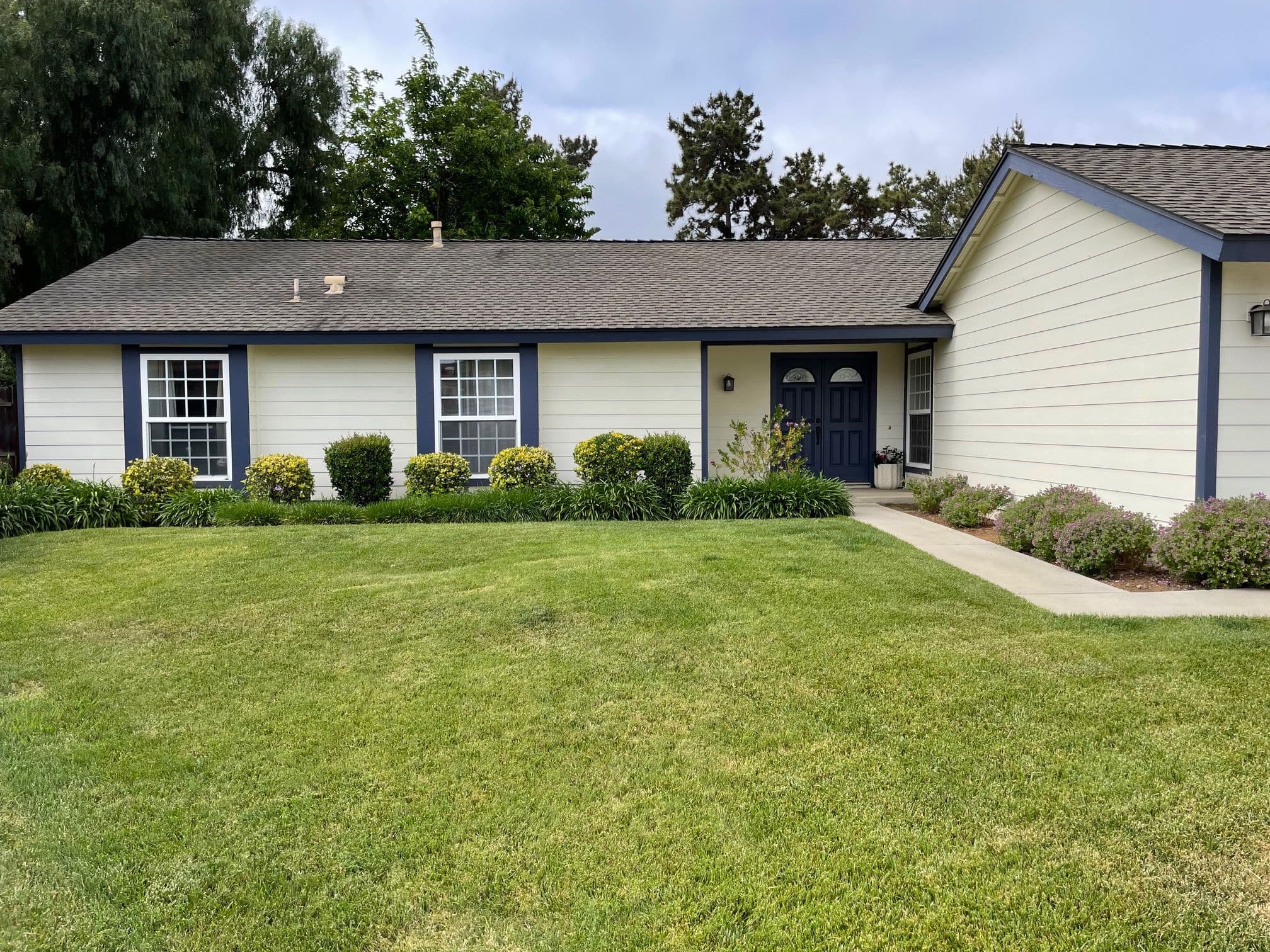 charming single-story home with blue trim, well-maintained lawn, and welcoming front entrance